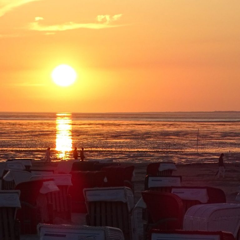 Sonnenuntergang über dem Meer mit Liegestühlen im Vordergrund in Bensersiel.